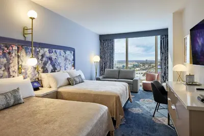 a hotel room with two beds and a desk at Universal's Helios Grand Hotel, a Loews Hotel in Orlando