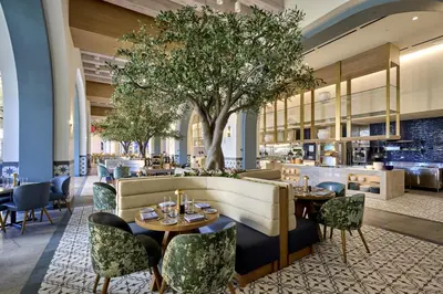 a restaurant with tables and chairs and a tree at Universal's Helios Grand Hotel, a Loews Hotel in Orlando