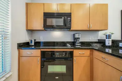 a kitchen with wooden cabinets and a microwave at 2 Suítes c/ Jacuzzi • 10min da Disney in Kissimmee
