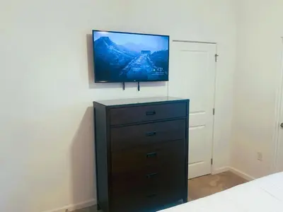 a bedroom with a dresser with a flat screen tv on the wall at Magic Kingdom Villa - Private Master Bedrooms in Kissimmee
