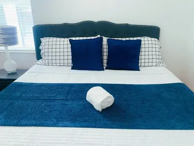 a white pillow sitting on a bed with blue pillows at Magic Kingdom Villa - Private Master Bedrooms in Kissimmee