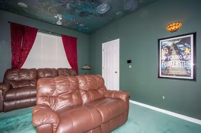 a living room with a leather couch and a window at Waterslide 6 bed Lux Villa Emerald Island in Kissimmee