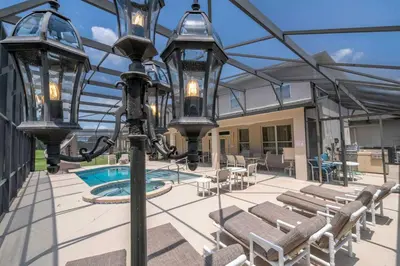 a patio with a light pole with chairs and a pool at Waterslide 6 bed Lux Villa Emerald Island in Kissimmee