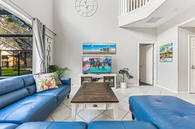 a living room with a blue couch and a table at 6 Bedroom Villa - Emerald Island Retreat in Kissimmee