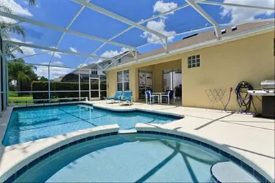 a swimming pool with an umbrella on a house at Just 3 miles from Disney! in Kissimmee