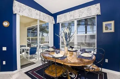 a dining room with a wooden table and blue walls at Just 3 miles from Disney! in Kissimmee