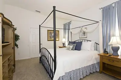 a bedroom with a black canopy bed with white pillows at Just 3 miles from Disney! in Kissimmee