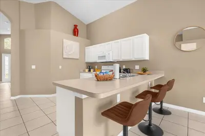 a kitchen with a counter and two stools at Summer Getaway - 5-Bedroom Home with Private Pool! in Kissimmee