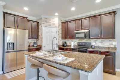 a kitchen with wooden cabinets and a large island with bar stools at WFH, Relax and Enjoy At-Home Comforts in Orlando in Kissimmee