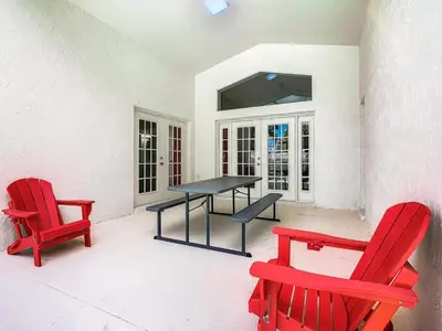 a patio with two red chairs and a table at Dreamy 5BR, 3Bath Getaway, Pool, Spa, Near Disney in Orlando