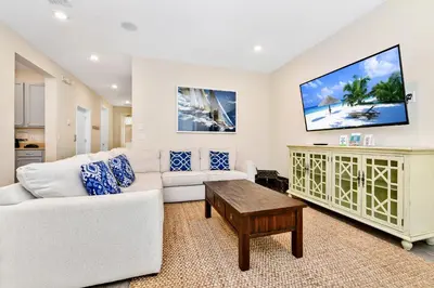 a living room with a white couch and a tv at Sunrise Cottage With Private Pool Near Disney With Margaritaville Resort & Island H2O Access - 8017Su in Orlando