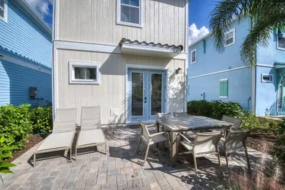 a patio with a table and chairs in front of a building at Seven Saturdays Cottage Near Disney With Margaritaville Resort & Island H2O Access - 3032Sp in Orlando