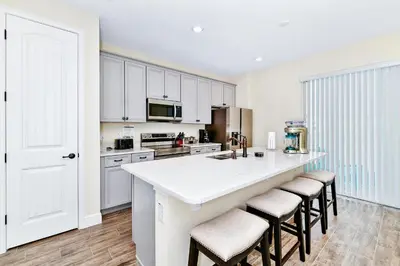 a kitchen with white cabinets and a large island with bar stools at Pearly White Villa Near Disney With Margaritaville Resort & Island H2O Access - 3061Cs in Orlando