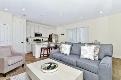 a living room with a gray couch and a kitchen at Summer Breeze Villa Near Disney With Margaritaville Resort & Island H20 Waterpark Access - 2960Cs in Orlando