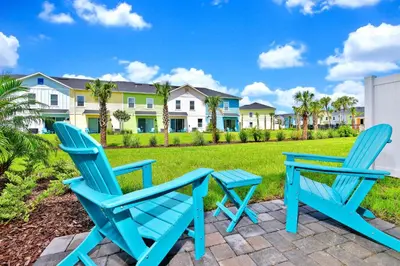 two blue chairs and a table on a patio in front of condos at Calming Villa Near Disney With Margaritaville Resort And Island H20 Waterpark Access - 2914Cl in Orlando