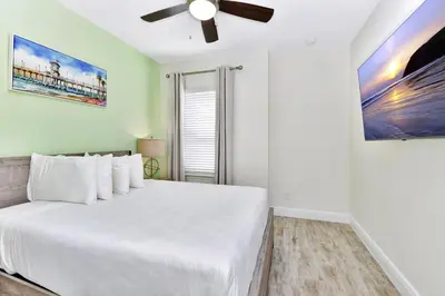 a bedroom with a white bed with a ceiling fan at Blissful Pink Villa Near Disney With Margaritaville Resort & Island H20 Access - 8103Cp in Orlando