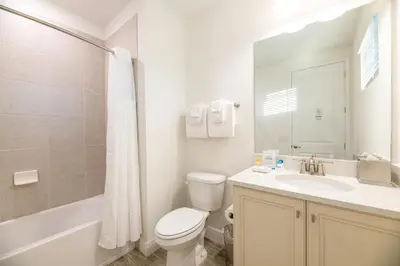 a white bathroom with a toilet and a sink at Vibrant Cottage With Private Pool Near Disney With Margaritaville Resort & Island H2O Access - 8043Kd in Orlando