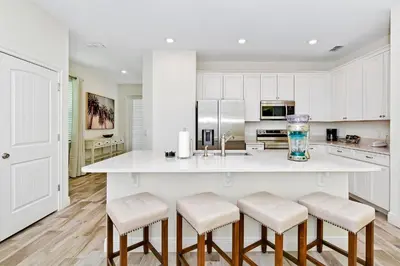 a kitchen with a large white island with stools at Cool Cottage Near Disney With Margaritaville Resort & Island H20 Waterpark Access - 3184Cs in Orlando