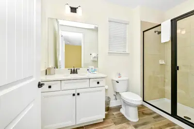 a white bathroom with a toilet and a sink at Beachy Daze Cottage Near Disney With Margaritaville Resort & Island H20 Waterpark Access - 2916Sr in Orlando