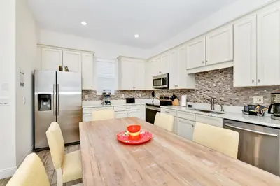 a kitchen with a wooden table and a refrigerator at Sunny Cottage Near Disney With Margaritaville Resort & Island H20 Waterpark Access - 3013Sp in Orlando