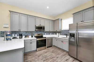 a kitchen with white cabinets and stainless steel appliances at Caraway Cove Cottage Near Disney With Margaritaville Resort & Island H2O Access - 8024Su in Orlando