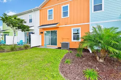 an orange house with a yard in front of it at Tropical Orange Villa Near Disney With Margaritaville Resort & Island H20 Waterpark Access - 2920Cs in Orlando