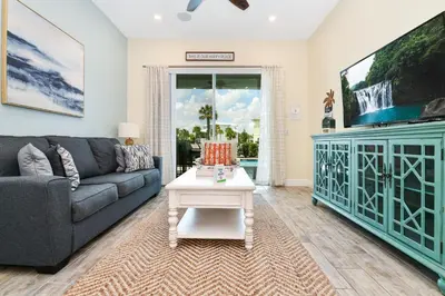 a living room with a couch and a table at Seashell Cream Cottage With Private Pool Near Disney With Margaritaville Resort & Island H2O Access - 8037St in Orlando