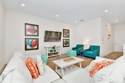 a living room with a white couch and a table at This Pink Cottage Near Disney With Margaritaville Resort & Island H20 Access - 8141Su in Orlando