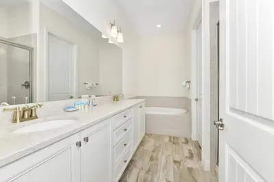 a white bathroom with a sink and a tub at This Pink Cottage Near Disney With Margaritaville Resort & Island H20 Access - 8141Su in Orlando