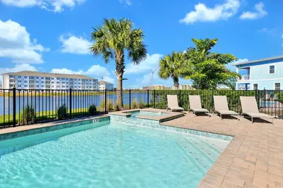 a swimming pool with lounge chairs and a fence at This Pink Cottage Near Disney With Margaritaville Resort & Island H20 Access - 8141Su in Orlando