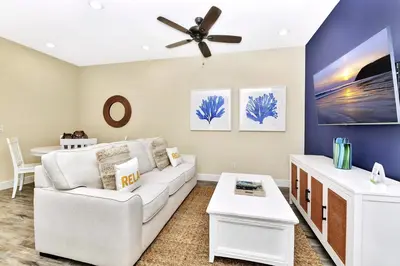 a living room with a white couch and a ceiling fan at Breezy Blue Villa Near Disney With Margaritaville Resort & Island H20 Waterpark Access - 2997Cs in Orlando