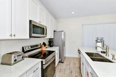 a kitchen with white cabinets and a stainless steel refrigerator at Blossom Villa Near Disney With Margaritaville Resort And Island H20 Waterpark Access - 2911Cl in Orlando