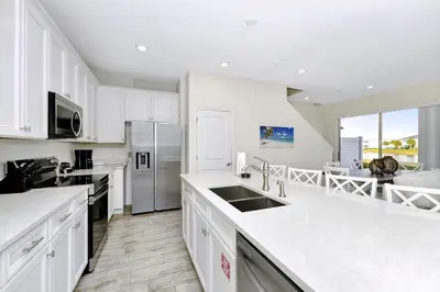 a kitchen with white cabinets and white counter tops at Flip Flops & Fairytales Waterfront With Margaritaville Resort & Island H2O & Island H2O Access - 3021Cs in Orlando
