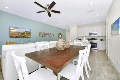 a kitchen and dining room with a wooden table and white chairs at Flip Flops & Fairytales Waterfront With Margaritaville Resort & Island H2O & Island H2O Access - 3021Cs in Orlando