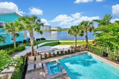 a swimming pool with palm trees and a body of water at Palm Tree Paradise Cottage Private Pool Near Disney With Margaritaville Resort & Island H20 Access - 8109Su in Orlando