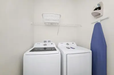 a laundry room with a washing machine and a basket on a shelf at Aqua Blue Cottage Near Disney With Margaritaville Resort & Island H20 Waterpark Access - 2930Sr in Orlando