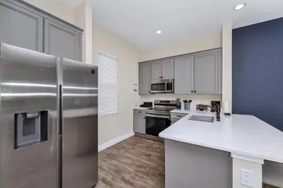 a kitchen with a stainless steel refrigerator and white cabinets at Aqua Blue Cottage Near Disney With Margaritaville Resort & Island H20 Waterpark Access - 2930Sr in Orlando