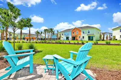 two blue chairs and a table on a patio with houses at Colorful Villa Near Disney With Margaritaville Resort & Island H20 Waterpark Access - 3140Cs in Orlando