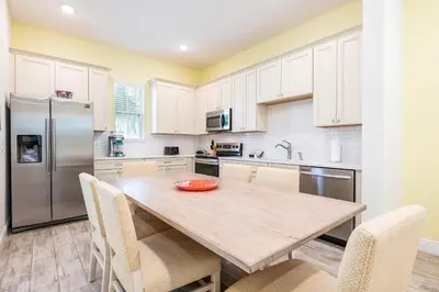 a kitchen with a wooden table with chairs and a refrigerator at Kokomo Cottage Near Disney With Margaritaville Resort & Island H2O Access - 8034Su in Orlando