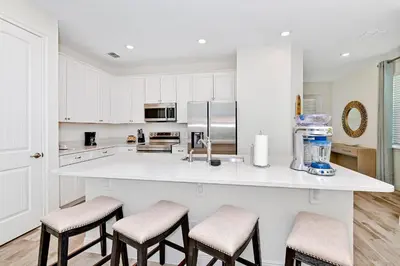 a kitchen with white cabinets and a counter with stools at Sea Blue Villa Near Disney With Margaritaville Resort & Island H20 Access - 3164Cs in Orlando
