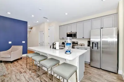 a kitchen with a counter with stools and a refrigerator at Welcoming Villa Near Disney With Margaritaville Resort & Island H20 Waterpark Access - 2943Cl in Orlando