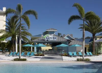 a resort with a swimming pool and chairs and palm trees at Sun Filled Villa Near Disney With Margaritaville Resort & Island H20 Access - 8119Cp in Orlando