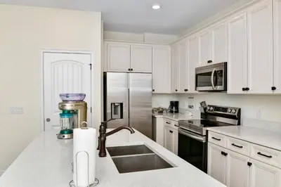 a kitchen with white cabinets and a stainless steel refrigerator at Sun Filled Villa Near Disney With Margaritaville Resort & Island H20 Access - 8119Cp in Orlando