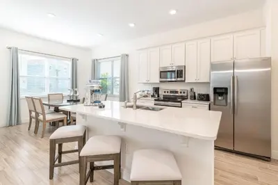 a kitchen with white cabinets and a large island with bar stools at Ocean Blue Cove Cottage Near Disney With Margaritaville Resort & Island H2O Access - 8020Ls in Orlando