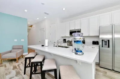a kitchen with white cabinets and a kitchen island with stools at Colorful Villa Near Disney With Margaritaville Resort & Island H20 Waterpark Access - 3128Cs in Orlando