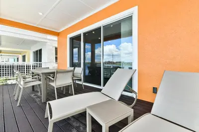 a patio with tables and chairs on a balcony at Waters Edge Cottage Near Disney With Margaritaville Resort & Island H20 Access - 8129Su in Orlando