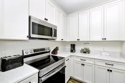 a kitchen with white cabinets and a stove and a microwave at Citrus Sunshine Villa Near Disney With Margaritaville Resort & Island H2O Access - 3049Cs in Orlando