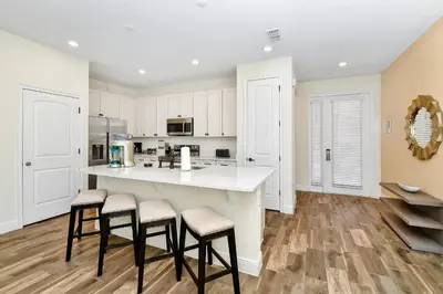 a kitchen with white cabinets and a large island with stools at Colorful Villa Near Disney With Margaritaville Resort & Island H20 Access - 8195Cp in Kissimmee