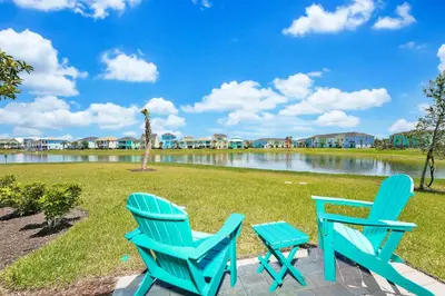 two blue chairs and a table next to a lake at Beautiful Waterfront Villa Near Disney With Margaritaville Resort & Island H20 Waterpark Access - 3017Cs in Orlando