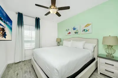 a bedroom with a white bed and a ceiling fan at Beautiful Waterfront Villa Near Disney With Margaritaville Resort & Island H20 Waterpark Access - 3017Cs in Orlando